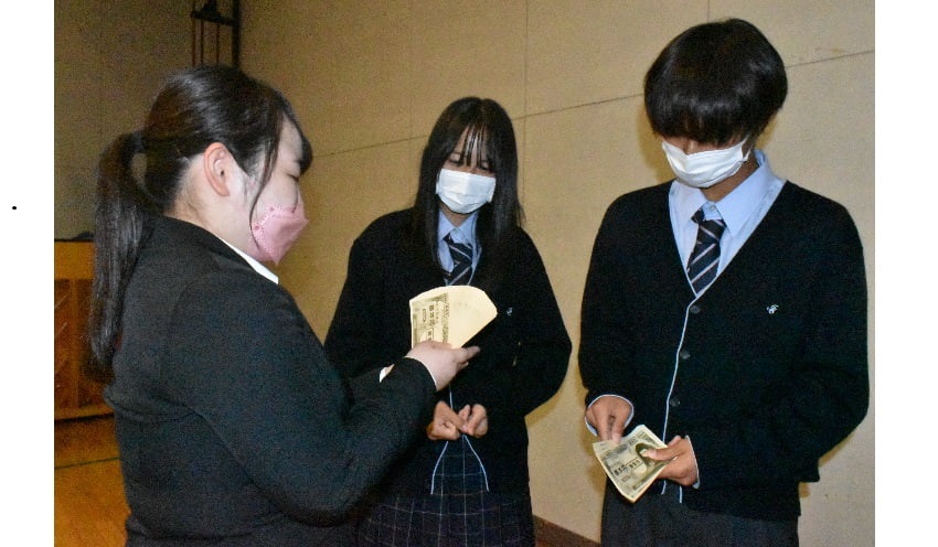 模擬紙幣を使って生徒に札勘定を披露する職員（左、10月6日、千葉県市川市の市川昴高校）